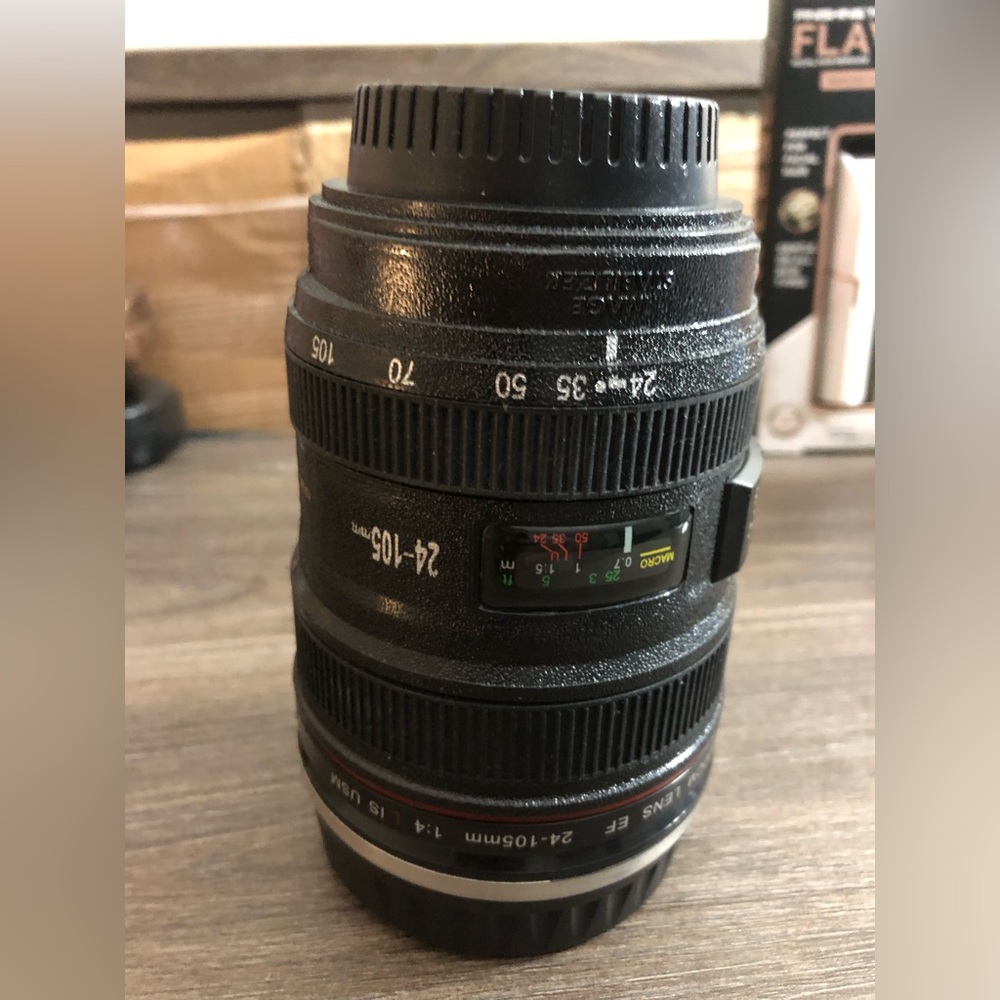 It’s a Tumbler! Shaped like a small black faux camera lense, with twist lid!